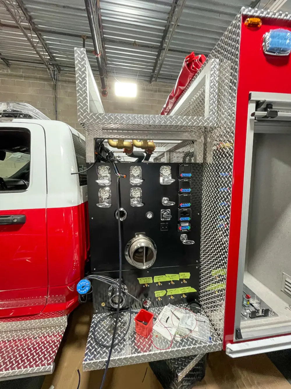 Exterior view of small fire truck showing cab, body compartments, and wheel/tire area.